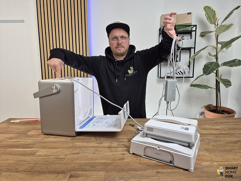 Smart Home Fox Experte haelt Stromkable des WINBOT Mini und drueckt den Knopf in der W2 OMNI Station